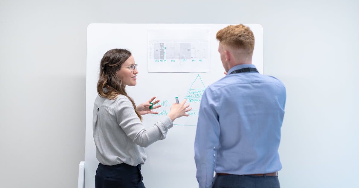 woman and man discussing before a whiteboard
