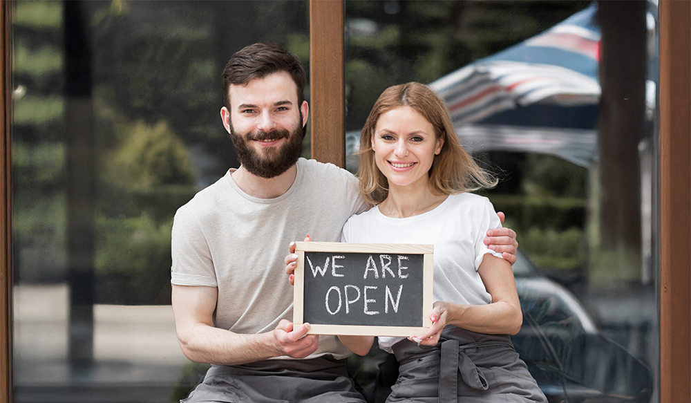Couple presenting their business open sign